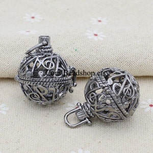May include: Two silver metal music note charm pendants with a hinged opening. The pendants are round and feature a delicate design of musical notes.