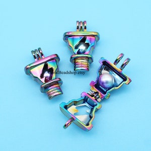 May include: Three iridescent rainbow-coloured metal charm pendants shaped like an electrical outlet with a lightning bolt design. The pendant on the right is open, revealing a pearl inside.