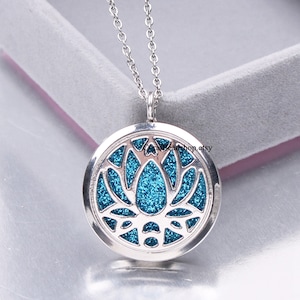 May include: Silver chain necklace with a round silver locket pendant. The locket has a blue glitter lotus flower design.