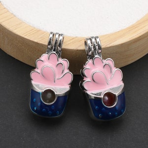 May include: Two silver charm pendants featuring a pink flower design and a blue base with white dots. The charms have a small clear glass bead in the centre.