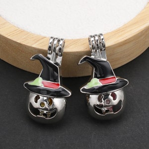 Può includere: Due ciondoli in metallo argentato a forma di zucche di Halloween con cappelli da strega neri. I cappelli presentano una fascia rossa e un dettaglio verde chiaro. I volti delle zucche hanno occhi e bocche intagliati e un gancio superiore.