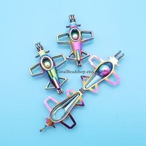 May include: Three iridescent rainbow-colored metal airplane charm pendants with a small pearl inside each. The charms are open on one side and can be used for a variety of crafts.