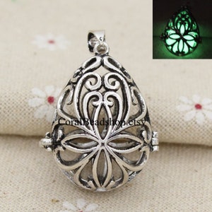 May include: Silver filigree pendant with a flower design. The pendant is open and can be used to hold a small object. The pendant glows in the dark.