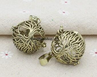 May include: Two antique gold-colored pendants. Each pendant is a sphere with a tree of life design. The tree's branches and roots are intricately detailed. The pendants have a loop at the top for a chain.