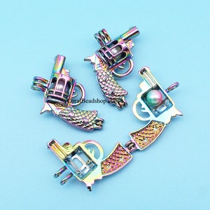 May include: Four iridescent gun-shaped pendants with pearl accents. The pendants are in various positions, showcasing the details of the barrel, trigger, and handle. The metallic finish reflects a spectrum of colors against a light blue background.