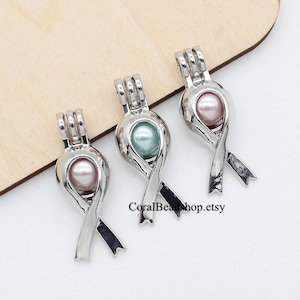 Puede incluir: Tres colgantes plateados en forma de lazo, cada uno con una perla rosa o verde. Los colgantes tienen un diseño de jaula para sujetar las perlas. El texto "CoralBeadshop.etsy" es visible. Adecuado para la creación de joyas.