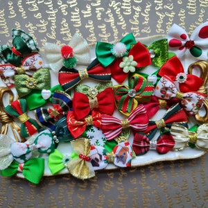 May include: A collection of 20 miniature Christmas bows in various colors and patterns, including red, green, gold, white, and black. The bows are arranged on a white plate with a gold rim.