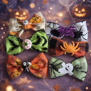 May include: A collection of six fabric hair bows featuring Halloween themes. Designs include pumpkins with a cat, a green bat pattern with an eyeball, orange pumpkins with a grim reaper, a spider web print with a purple spider, orange plaid with an orange spider, and a green web print with a white ghost.