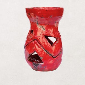 May include: A vibrant red ceramic vase with a textured surface and geometric cutouts. The vase has a wide top and a rounded base, with a height of approximately 8 inches.