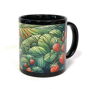 Peut inclure: Un mug en céramique noire orné d'une illustration colorée d'un champ de fraises. Le motif présente des feuilles vertes détaillées et plusieurs fraises rouges nichées dans le feuillage, avec une anse et un bord intérieur noirs.