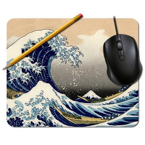 May include: Mouse mat with a print of Hokusai's "The Great Wave off Kanagawa", featuring a large blue wave, boats, and Mount Fuji. A black computer mouse and a yellow pencil are on the mat. The mat is rectangular.