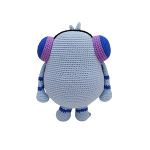 May include: A light blue crocheted stuffed toy with purple and blue ears and blue and white striped legs. The toy has a black crocheted headband.