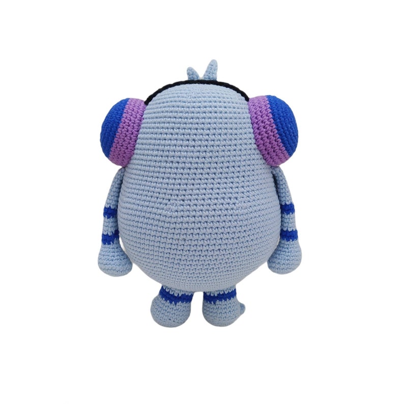 May include: A light blue crocheted stuffed toy with purple and blue ears and blue and white striped legs. The toy has a black crocheted headband.