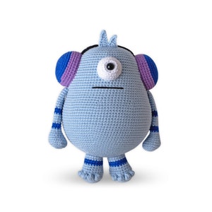 May include: A blue crocheted monster toy with purple and blue striped ears, one white eye with a black pupil, and blue and white striped legs.