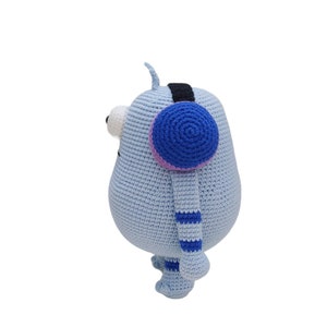 May include: A light blue crocheted stuffed toy with a blue and pink ear warmer, blue and white striped legs, and a single large white eye.