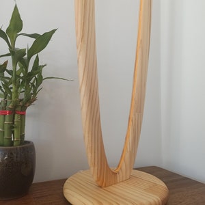 May include: A wooden table lamp with a unique curved design. The lamp base is made of natural wood and has a smooth, rounded finish.