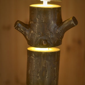 May include: A rustic, wooden lamp with a unique design. The lamp is constructed from stacked, cylindrical wooden pieces, with a branch-like element. Each section emits a warm, inviting light, creating a cozy ambiance. The lamp's natural wood tones and texture add a touch of nature to any space.