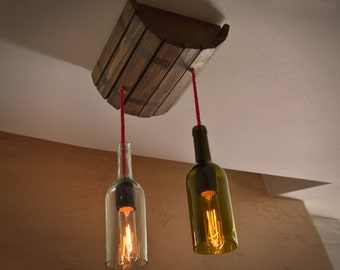 May include: A unique pendant light fixture made from repurposed wine bottles. The fixture features two glass bottles suspended from a wooden barrel-shaped mount. Red cords hold the bottles, each with a warm-toned Edison bulb. The fixture is mounted on a white ceiling.
