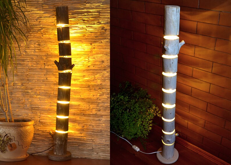 May include: A rustic floor lamp crafted from a section of a tree trunk. The lamp is segmented, with each section separated by a glowing light. The lamp has a natural wood finish and a round base.