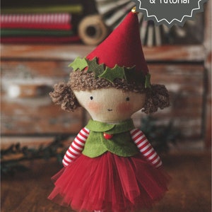 May include: A handmade elf doll with brown curly hair, wearing a red and white striped shirt, a green vest, a red tulle skirt, and a red hat with green holly leaves. The doll is standing on a wooden surface. PDF Pattern & Tutorial.