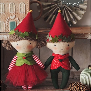 May include: A PDF pattern and tutorial for making two elf dolls. The dolls are dressed in red, green, and white. The girl doll has a red skirt and a green vest. The boy doll has a green vest and a red shirt with gold stars. Both dolls have holly wreaths around their hats.