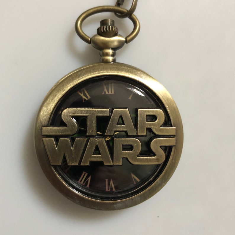 bronze pocket watch with the star wars logo on the front with the watch face visible in roman numerals