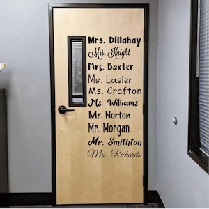 May include: A light-colored wooden door featuring a black rectangular window and a black handle. The door displays a vertical list of names in black lettering, including Mrs. Dillahay, Mrs. Knight, Mrs. Baxter, Ms. Laster, Ms. Crafton, Ms. Williams, Mr. Norton, Mr. Morgan, Mr. Smithton, and Mrs. Richards.