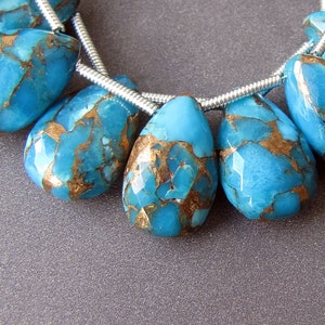 Op de afbeelding: Een streng turquoise edelsteen kralen met gouden vlekken. De kralen zijn gefacetteerd en hebben een traanvorm. De kralen zijn geregen op zilverdraad.