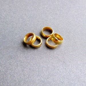 以下が含まれることがあります： 灰色の表面に、金色の金属製のリングが4つ重ねられています。