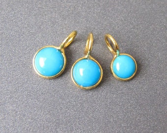 May include: Three gold charms with blue cabochon stones. The charms are different sizes, with the largest charm on the left and the smallest charm on the right.