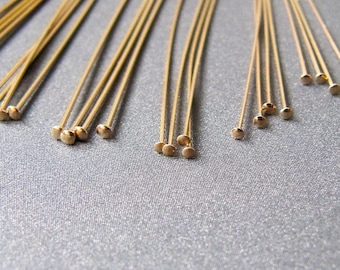 May include: A collection of gold-colored head pins, also known as T pins, with rounded heads. These pins are used for crafts, jewelry making, and other projects.
