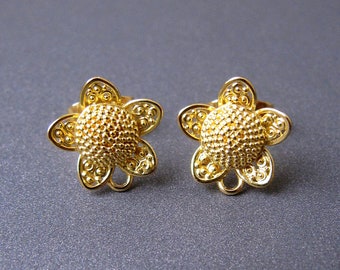 以下が含まれることがあります： 金色の花の形をしたイヤリングのペア。イヤリングはテクスチャ加工された表面と繊細なデザインをしています。