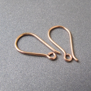 May include: Two rose gold earring hooks. The hooks are made of metal and have a teardrop shape.