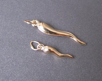 May include: Two gold-colored Italian horn charms, one larger than the other, on a gray background.