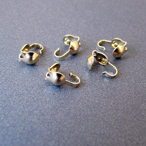 Op de afbeelding: Vijf goudkleurige metalen sluitingen voor het maken van sieraden. Elke sluiting heeft aan het ene uiteinde een kleine bal en aan het andere uiteinde een haak.