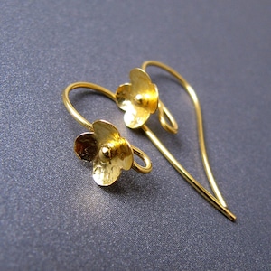 May include: A pair of gold earrings with a delicate flower design. The earrings are made of thin wire and have a simple, elegant style.