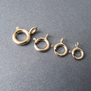 May include: Four gold-toned metal lobster clasps of different sizes. The clasps are arranged in order of size from largest to smallest.