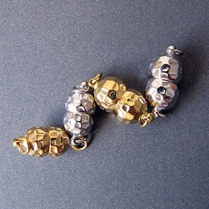 May include: A silver and gold bracelet with a textured, hammered finish. The bracelet is made up of alternating silver and gold beads.