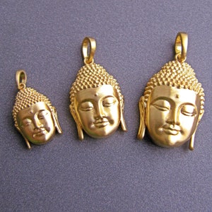 May include: Three gold-colored pendants featuring the face of Buddha. The pendants are different sizes, with the largest pendant in the center and the smallest pendant on the left.