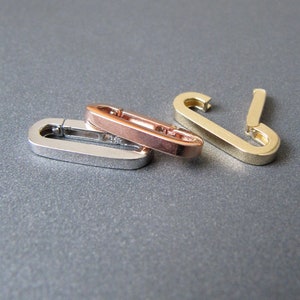 May include: Three metal clasps in silver, rose gold, and gold. The clasps are oval shaped and have a spring-loaded opening.