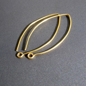 Op de afbeelding: Twee gouden oorringdraden, elk met een kleine lus aan het uiteinde. De draden zijn licht gebogen.