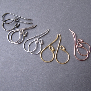 Könnte beinhalten: Ein Satz mit sechs Ohrhaken in vier verschiedenen Metalloberflächen: Schwarz, Silber, Gold und Roségold. Die Haken sind alle gleich groß und in der gleichen Form, mit einer kleinen Schlaufe oben und einer kleinen Kugel unten.