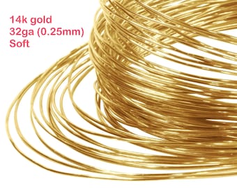 May include: Coiled 14k gold wire, 32 gauge (0.25mm), soft. The wire is a bright, warm gold color, tightly wound in a circular pattern. The text "14k gold 32ga (0.25mm) Soft" is visible in the upper left corner.