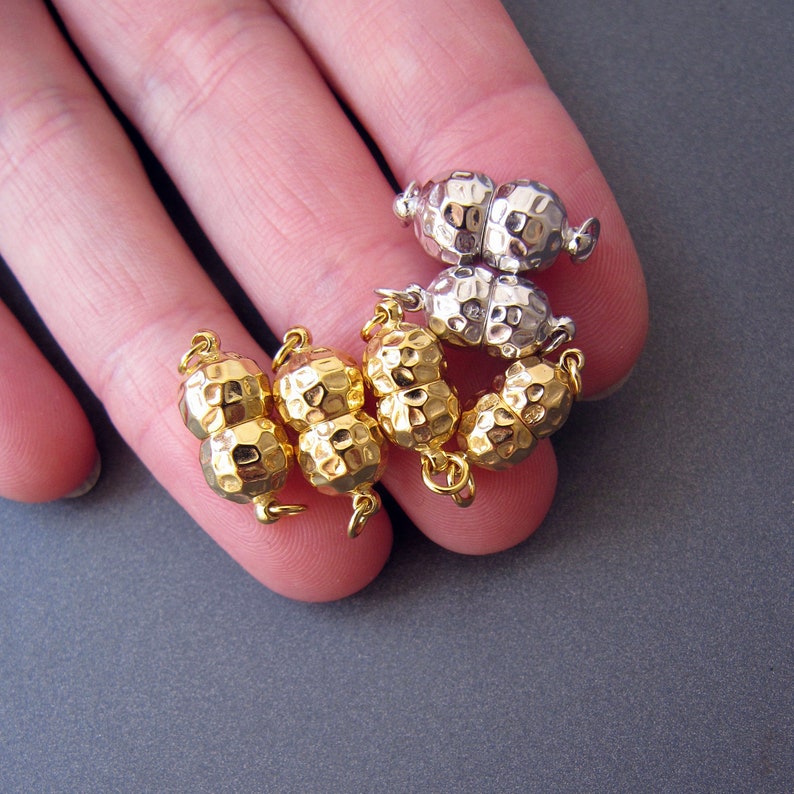 Op de afbeelding: Een set gouden magnetische sluitingen voor het maken van sieraden. De sluitingen zijn gemaakt van twee ronde, getextureerde stukken die met een magnetische sluiting aan elkaar worden bevestigd.