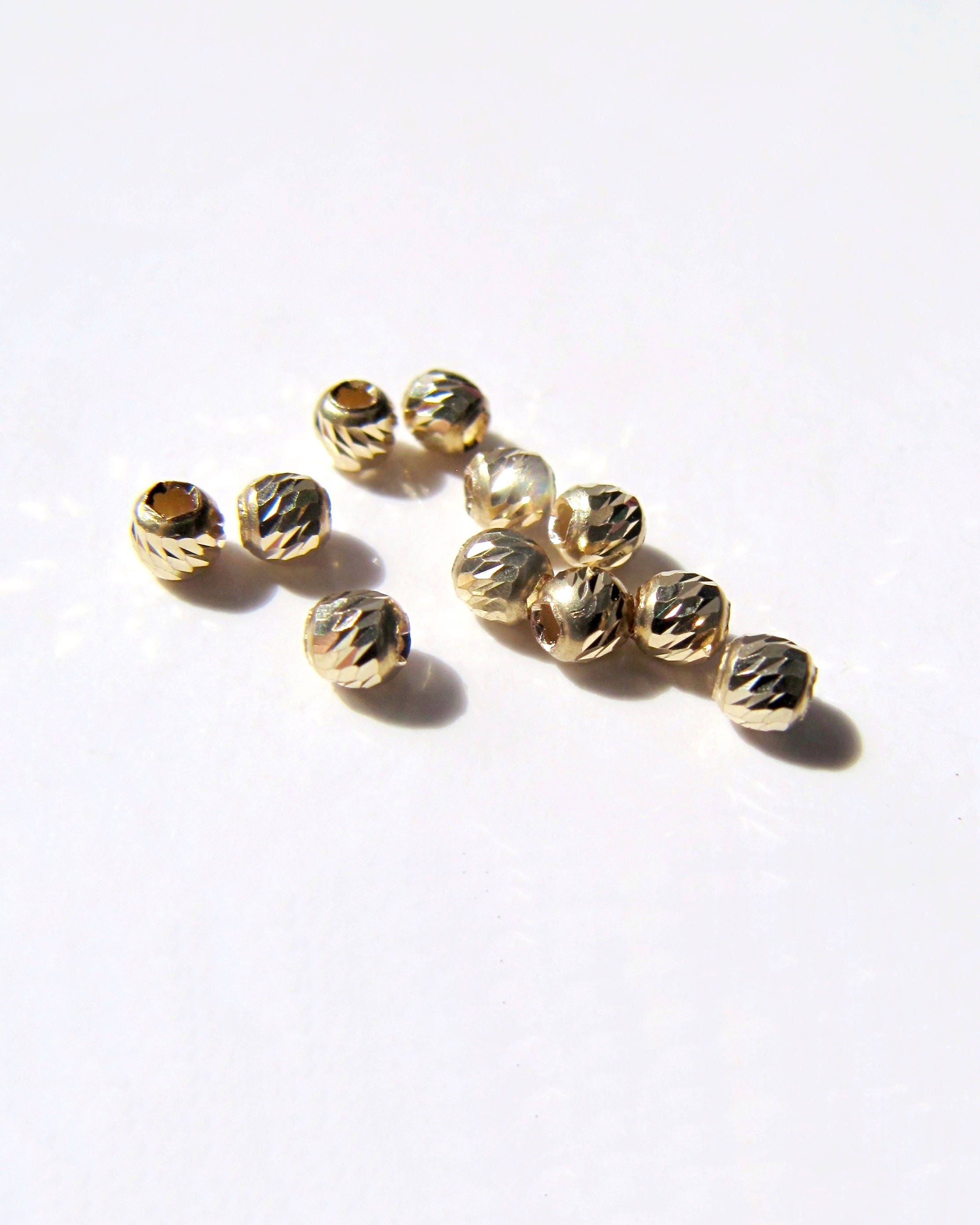 Bead, 12Kt gold-filled, 4mm faceted round. Sold per pkg of 100. - Fire  Mountain Gems and Beads
