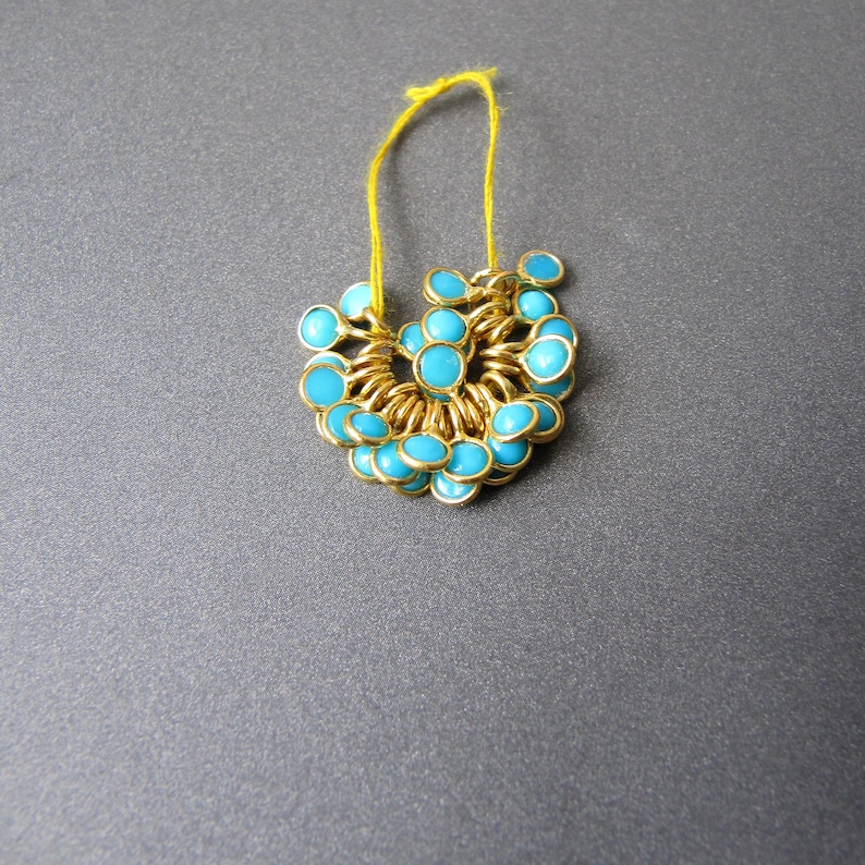 May include: A gold chain necklace with turquoise blue beads. The necklace is strung with small, round beads that are evenly spaced.