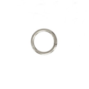 Puede incluir: Un anillo partido circular de color plateado, diseñado para sujetar objetos. El anillo es de metal y presenta una pequeña abertura para una fácil fijación. El anillo partido se muestra sobre un fondo blanco.