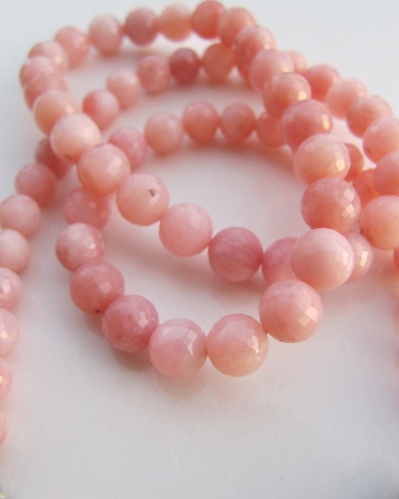 Op de afbeelding: Een ketting of armband gemaakt van roze opaal kralen, gefacetteerd en gepolijst, met een lichtroze tint.