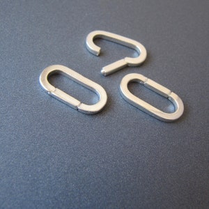 May include: Three silver oval-shaped jump rings, each with a slightly different size and shape.