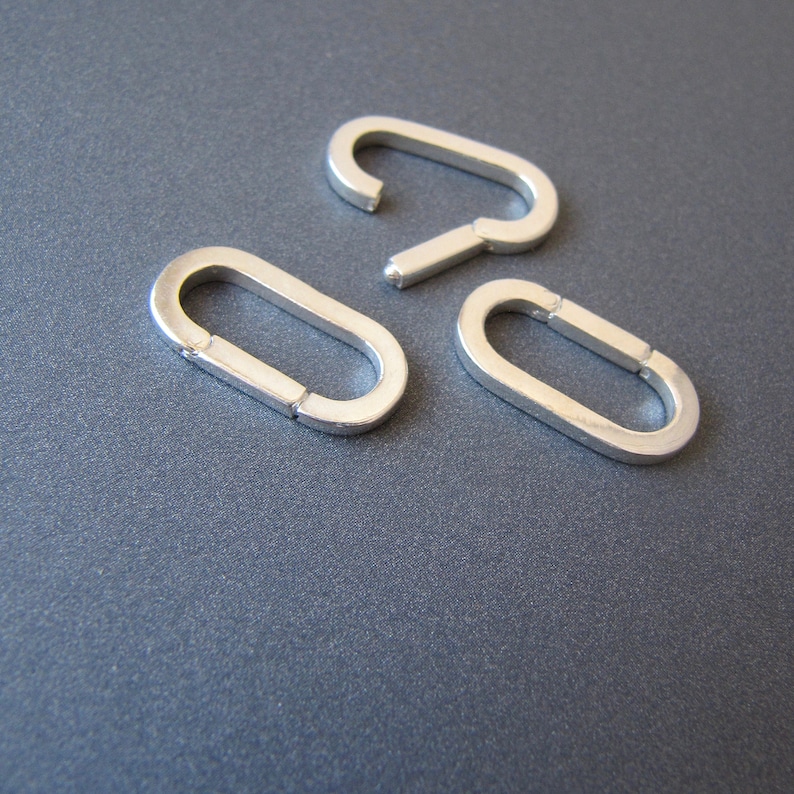 May include: Three silver oval-shaped jump rings, each with a slightly different size and shape.